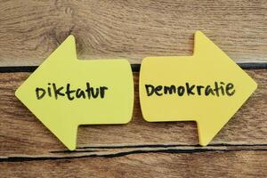 concept de diktature ou démocratie dans Langue Allemagne écrire sur gluant Remarques isolé sur en bois tableau. photo