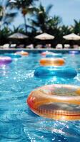été vacances dans un Extérieur bassin avec bleu l'eau sur une chaud ensoleillé journée avec flottant coloré gonflable anneaux. verticale image photo