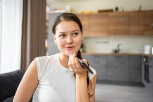 Jeune femme parle une voix message sur sa téléphone intelligent tandis que séance sur le canapé à Accueil photo