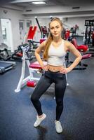 Jeune sportif femme portant tenue de sport posant avant Faire exercice avec aptitude équipement à salle de sport, elle exercice pour fort et bien . haute qualité photo