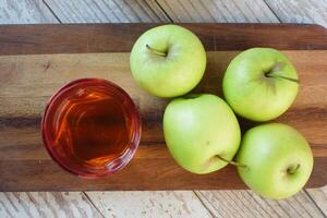 vinaigre de pomme en bouteille de verre avec pomme verte fraîche sur table photo