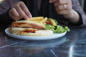 sandwich ou pain grillé avec saucisse servi sur une assiette sur carrelage Contexte photo