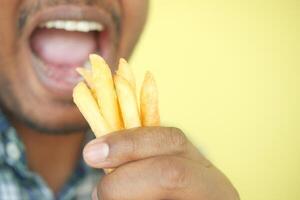 Jeune homme en mangeant français frites proche en haut photo