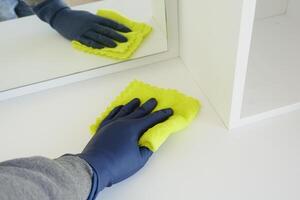 Main dans la table de nettoyage des gants en caoutchouc bleu avec un chiffon photo