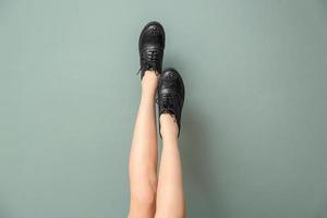 jambes de jeune femme dans des chaussures décontractées élégantes sur fond de couleur