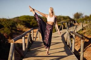 femme de race blanche pratiquant le yoga sur un pont en bois. photo