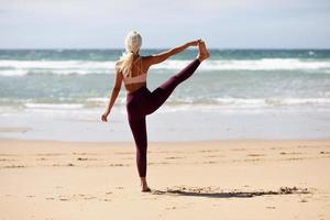 femme blonde caucasienne pratiquant le yoga sur la plage photo