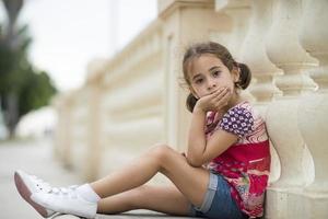 adorable petite fille coiffée de nattes assise sur le sol photo