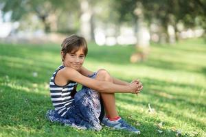 petite fille, huit ans, assise sur l'herbe à l'extérieur. photo