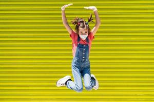 enfant fille sautant portant un masque de protection contre le coronavirus photo