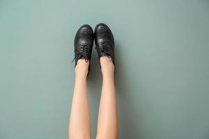 jambes de jeune femme dans des chaussures décontractées élégantes sur fond de couleur