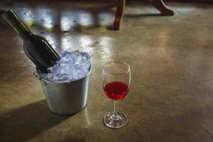 bouteille de vin rouge dans un seau à glace et un verre de vin rouge photo