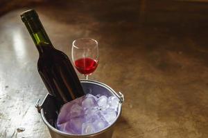 bouteille de vin rouge dans un seau à glace et un verre de vin rouge photo