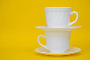 tasses en céramique blanche avec soucoupes sur fond jaune