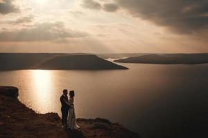 couple de mariage, la mariée et le marié se tenant la main sur un fond de montagnes et de rivières photo