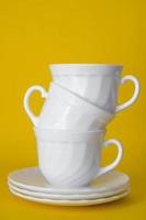 tasses en céramique blanche avec soucoupes pyramide pliée sur fond jaune