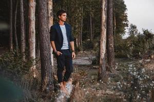 homme posant à l'extérieur dans la forêt se tient pieds nus sur une bûche, portant une veste à carreaux photo