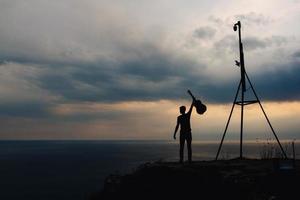 silhouette d'un homme tenant une guitare sur fond de nuages et de mer photo