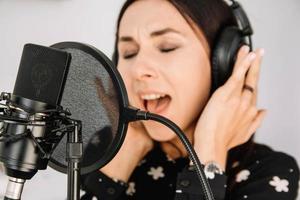 belle femme au casque chante une chanson près d'un microphone dans un studio d'enregistrement. place pour le texte ou la publicité photo