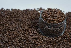 grains de café dans un bocal en verre parmi les grains de café photo