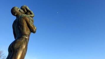 Östersund, Suède, Mars 11, 2022. le bronze statue de une homme en portant une enfant vers le après midi lune. photo