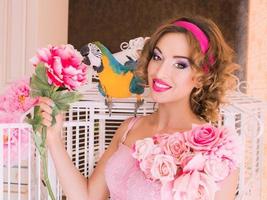 portrait de belle jeune femme en robe colorée avec des fleurs en style poupée avec ara sur son épaule photo