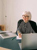 femme senior aux beaux cheveux gris dans son bureau. travail, personnes âgées, problèmes, affaires, concept d'expérience photo