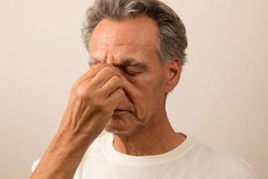 homme âgé souffrant de douleurs aux sinus se frottant le nez pour se soulager photo