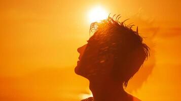 une mans silhouette avec le sien cheveux ébouriffé contre une vibrant le coucher du soleil ciel, capturer une moment de sérénité. photo