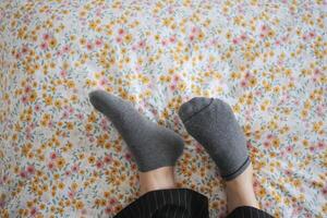 une femme est pose sur une lit avec leur pieds en haut et portant chaussettes photo