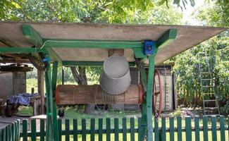 un ancien puits d'eau avec un seau dans le jardin, une poignée en métal pour soulever l'eau du sol. village bien sous le toit avec une corde. rétro bien à la campagne. photo