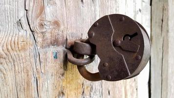 vieux cadenas en métal vintage sur une porte en bois fermée d'une ancienne ferme. le vrai style du village. fermer. se concentrer sur le château. fond en bois, texture. espace de copie photo