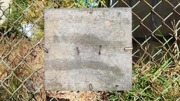 ancienne plaque de bois carrée fissurée sur un vieux treillis métallique. place pour votre texte ou logo. espace de copie photo