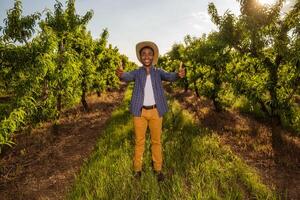 portrait de Afro-américain agriculteur dans le sien verger. il est cultiver prune. photo