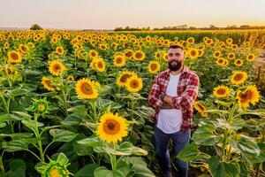 content agriculteur est permanent dans le sien tournesol champ lequel est dans fleurir. il est content car de bien saison et bien le progrès de le les plantes. photo