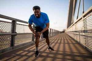 Jeune Afro-américain homme est blessé tandis que jogging. il a douleur dans genou. photo