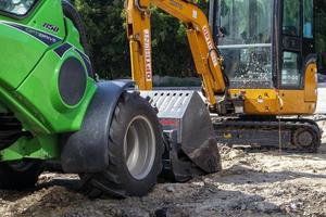 deux petites pelles sur un grand chantier de construction. vert vif sur les roues et jaune sur les pistes. terrassement et construction. pelle excavatrice. mini-chargeurs. ukraine, kiev - 28 août 2021. photo