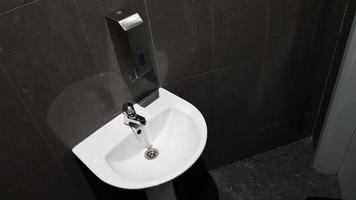 lavabo en céramique blanche avec robinet chromé dans les toilettes avec carrelage gris photo