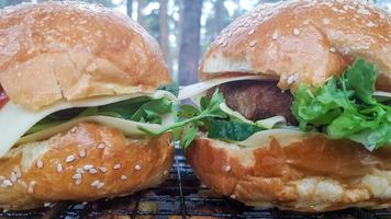 gros plan de deux gros hamburgers de bricolage dans le parc sur un barbecue, repos et cuisson sur un pique-nique en été, nourriture, délicieuses couleurs vives. concept de nourriture malsaine. Fast food. photo