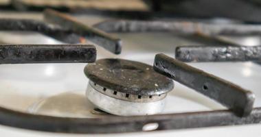 cuisinière à gaz sale dans la cuisine pour cuisiner avec des taches d'huile végétale et des débris d'aliments brûlés à la surface, gros plan. mise au point sélective. plaque de cuisson au gaz recouverte de graisse dans la cuisine. photo