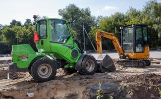 deux petites pelles sur un grand chantier de construction. vert vif sur les roues et jaune sur les pistes. terrassement et construction. pelle excavatrice. mini-chargeurs. ukraine, kiev - 28 août 2021. photo