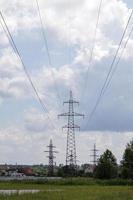 tour électrique haute tension. lignes électriques et pylônes électriques par une journée ensoleillée avec des nuages circulaires dans le ciel bleu. supports de ligne de transmission d'énergie haute tension. ils ont une structure en acier complexe. photo