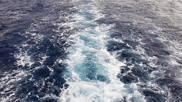 bateau de croisière ou sentier à la surface de la mer rouge bleue. sentier de bateau d'eau de mer avec une vague mousseuse blanche. vue de dessus de l'océan profond. perspective d'une vague d'eau vive. photo