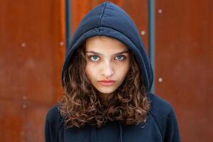 blanc brunette adolescent fille avec frisé cheveux pose sur le rue dans le ville. photo