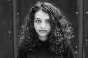 blanc brunette adolescent fille avec frisé cheveux pose sur le rue dans le ville. photo