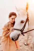 une blanc cheval et une femme dans une robe supporter sur une plage, avec le photo