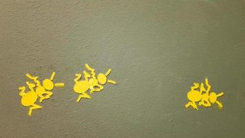 fourmi peinte en jaune sur un mur gris. fourmi escaladant un mur. arrière-plans de fourmis colorés. des artistes locaux décorent les murs des rues. photo