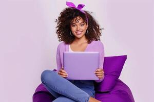 sur de soi Jeune femme avec frisé brunette cheveux en portant une portable tandis que assise sur une violet pouf photo