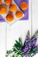 délicieux muffins et violet lupin fleurs sur blanc en bois Contexte. photo