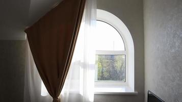 fenêtre cintrée dans le salon avec tulle et rideau. intérieur de chambre moderne et lumineux. photo